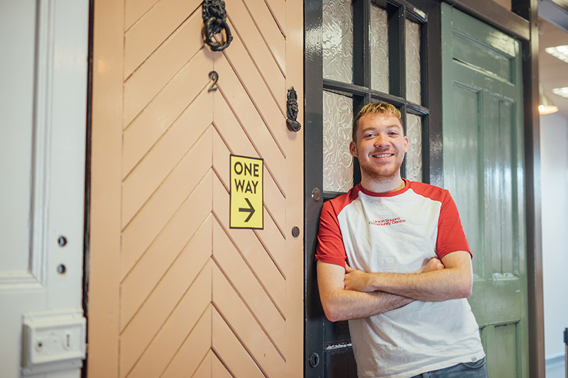 Image of student leaning against a set of doors, with 