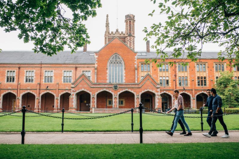 Four staff and students walking across the Queen's Quadrangle