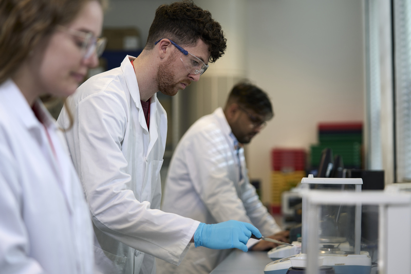 Three researchers conducting tests in lab